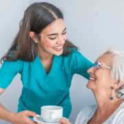 Carer serving coffee to an elderly woman
