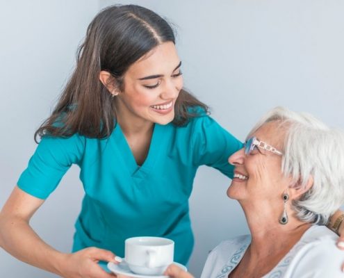 Carer serving coffee to an elderly woman