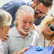 Family giving a present to an elderly man